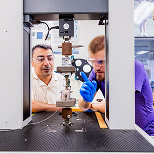 A photo of two people examining a machine in a lab.