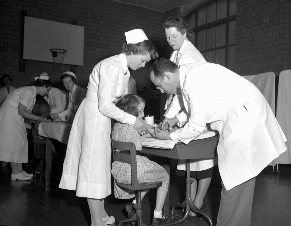 A photo of nurses and a doctor treating a polio patient.