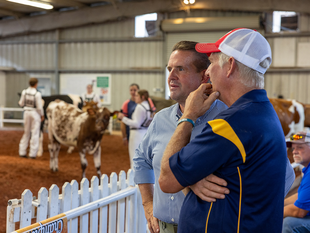WVU President Michael T. Benson at the State Fair of West Virginia in front of a cattle show.